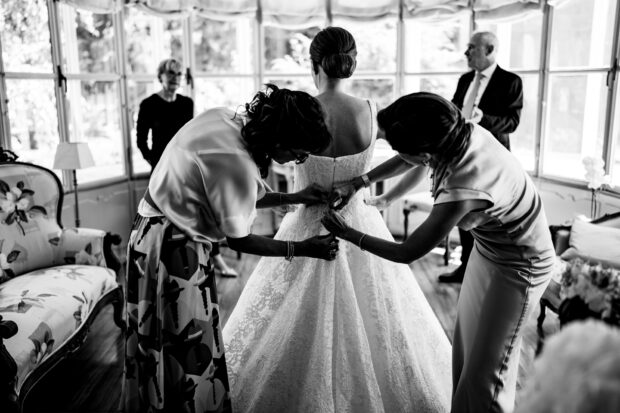 Le amiche aiutano la sposa ad allacciare l’abito prima del matrimonio a Villa Gaia Gandini.