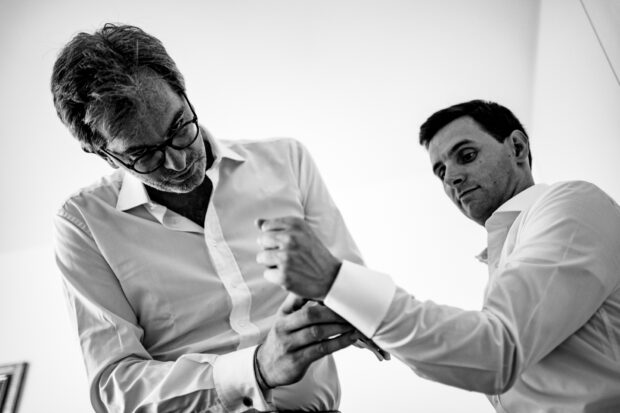 Il testimone aiuta lo sposo ad allacciare il polsino con i gemelli prima del matrimonio a Villa Gaia Gandini.