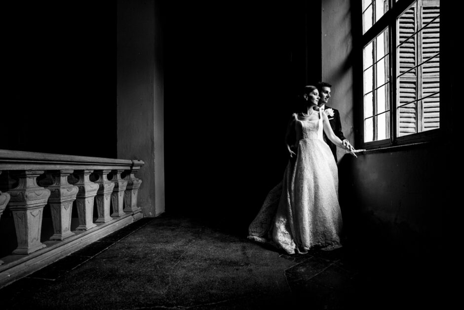 Gli sposi in un ritratto in bianco e nero alla finestra di Villa Gaia Gandini.