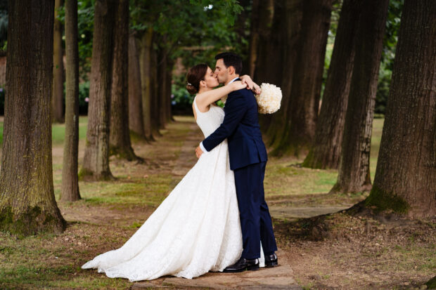Gli sposi si baciano tra i filari di alberi nel parco di Villa Gaia Gandini.