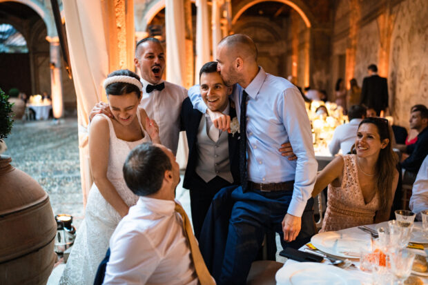 Gli amici festeggiano lo sposo con baci e abbracci durante il matrimonio.