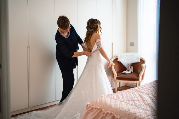 La madre aiuta la sposa ad allacciare il vestito prima della cerimonia al Castelletto di Corbetta.