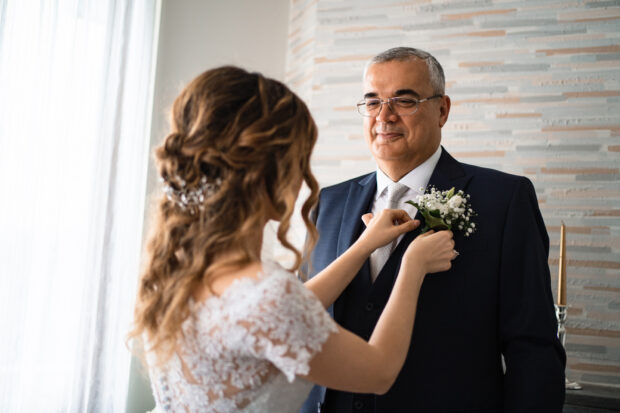 La sposa sistema la bottoniera sul completo del padre prima della cerimonia al Castelletto di Corbetta.
