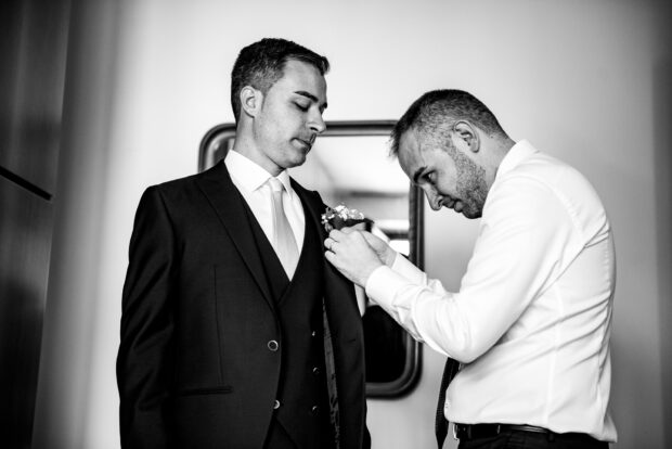 Il fratello aiuta lo sposo a indossare la giacca prima del matrimonio al Castelletto di Corbetta.