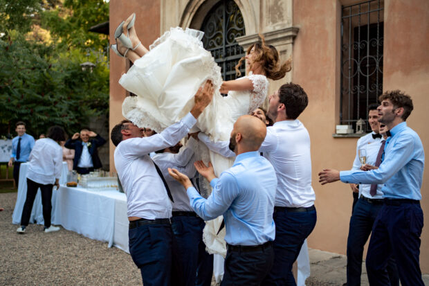 Gli amici sollevano in aria la sposa durante il ricevimento al Castelletto di Corbetta.
