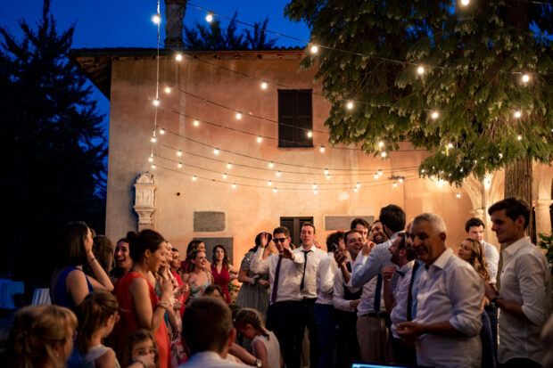 Il cortile del Castelletto di Corbetta illuminato di notte, mentre gli invitati si divertono con giochi e balli.