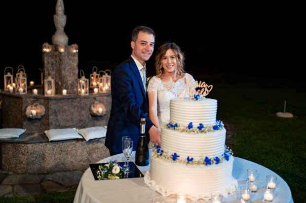 Gli sposi tagliano la torta nuziale sotto un cielo di lucine al Castelletto di Corbetta.