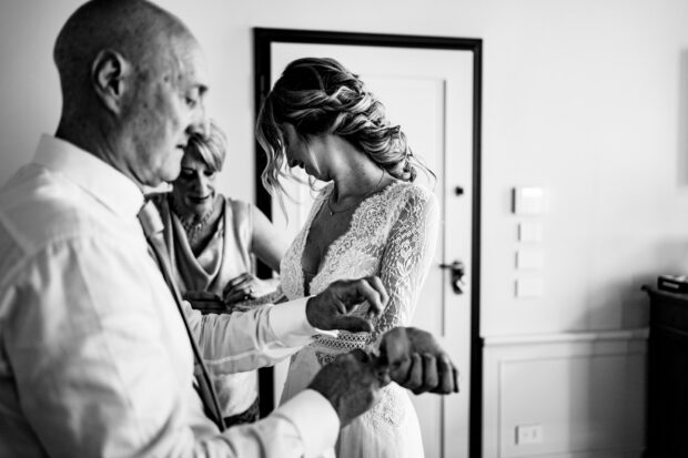 La sposa indossa il suo abito con l’aiuto del papà prima del matrimonio Borgo della Rocca.