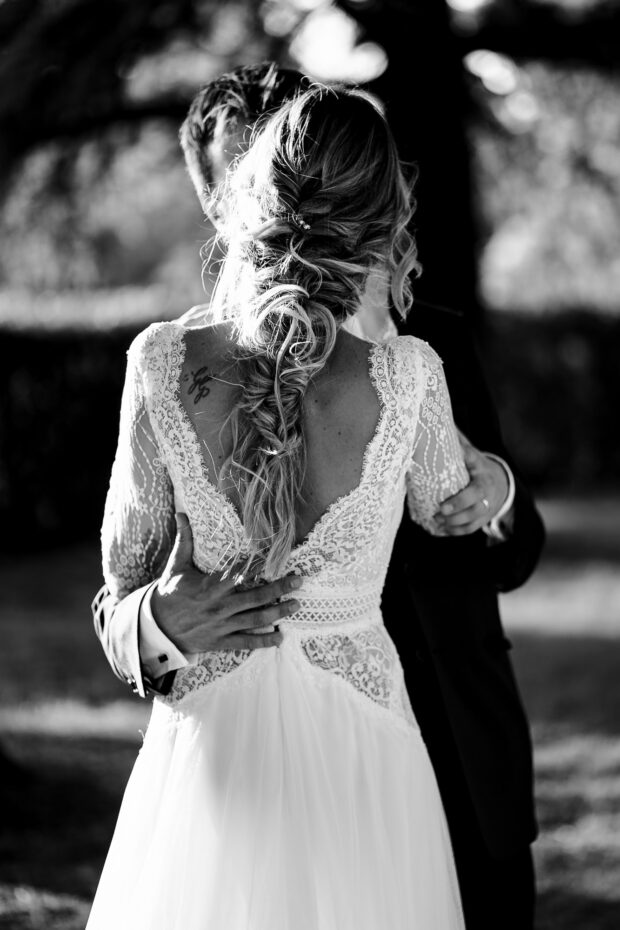 Il romantico abbraccio dello sposo mentre la sposa mostra la raffinatezza del suo abito durante il matrimonio Borgo della Rocca.