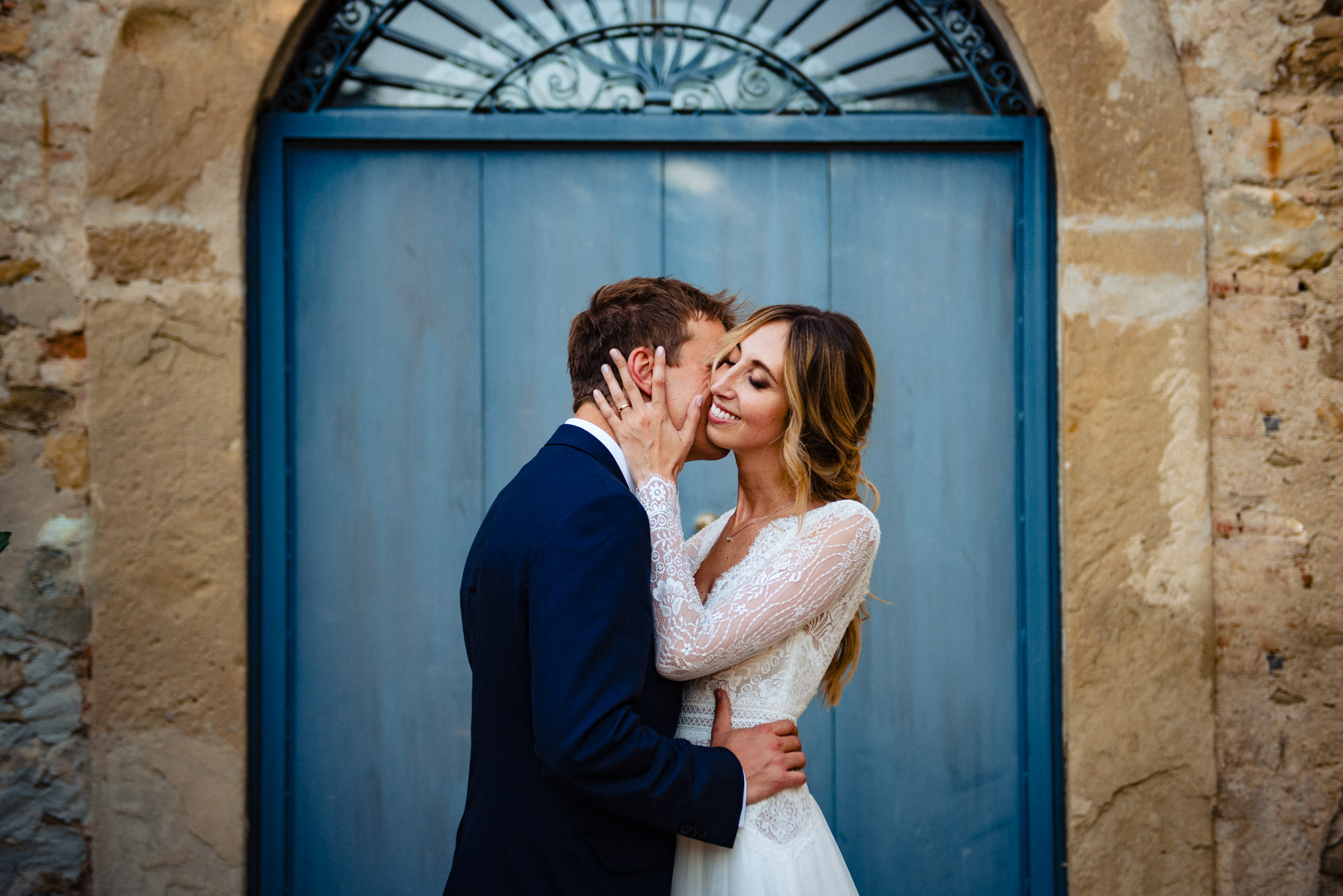 Gli sposi posano elegantemente davanti a una porta azzurra, creando un ritratto sofisticato nel matrimonio Borgo della Rocca.