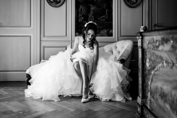 Dettaglio bianco e nero della sposa che infila le scarpe