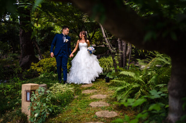 Gli sposi passeggiano mano nella mano nel giardino giapponeseRitratto ampio degli sposi nel giardino giapponese - fotografo matrimonio villa paradeisos, tra le Migliori Location Matrimonio Varese.