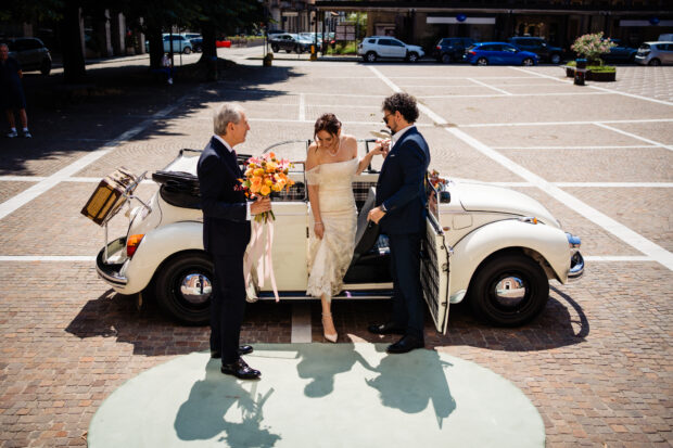 La sposa scende da un Maggiolone vintage davanti alla chiesa.