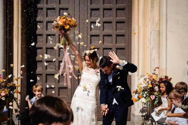 Gli sposi escono dalla chiesa sotto una pioggia di petali.