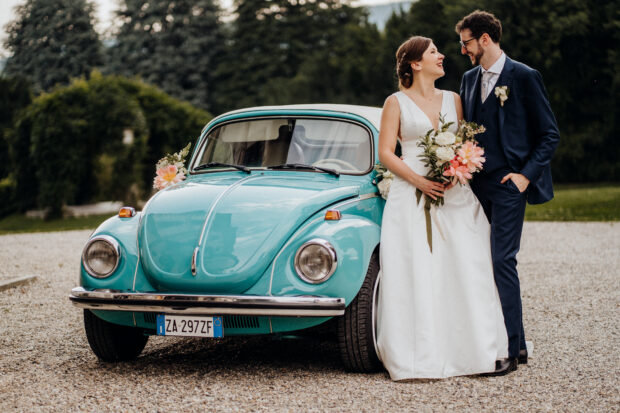 Carolina e Giulio posano accanto all’auto d’epoca del loro matrimonio a Villa Borghi